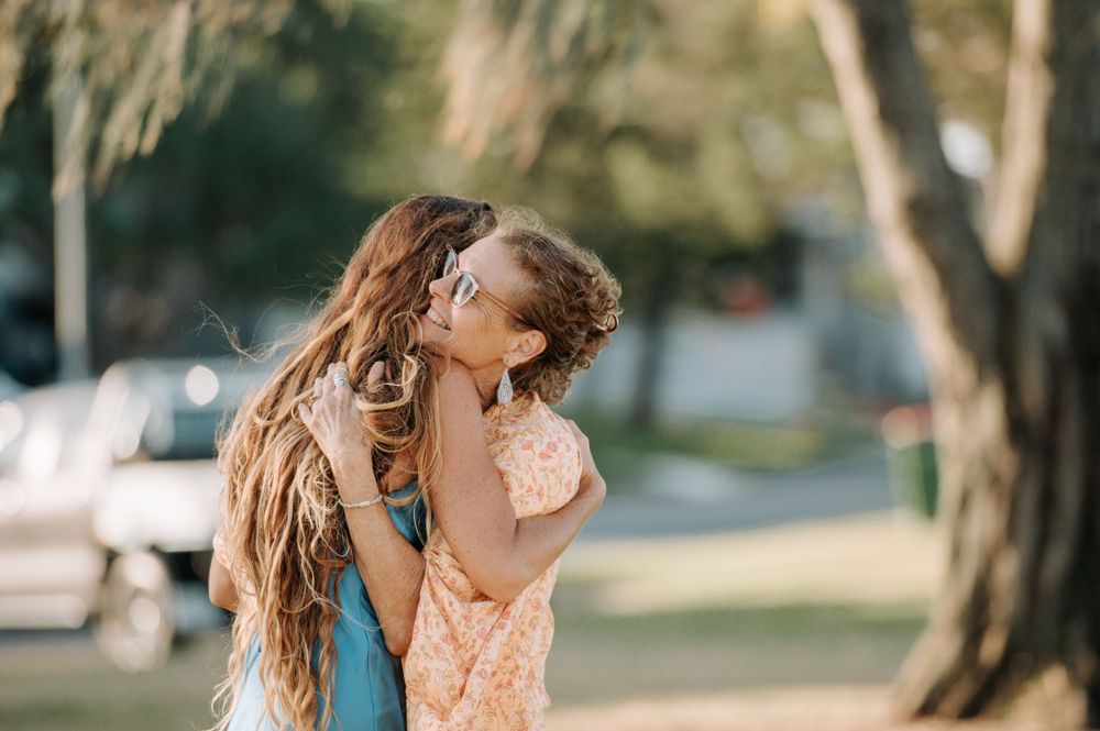 A joyful moment captured between mother and daughter with long flowing hair in an outdoor setting.