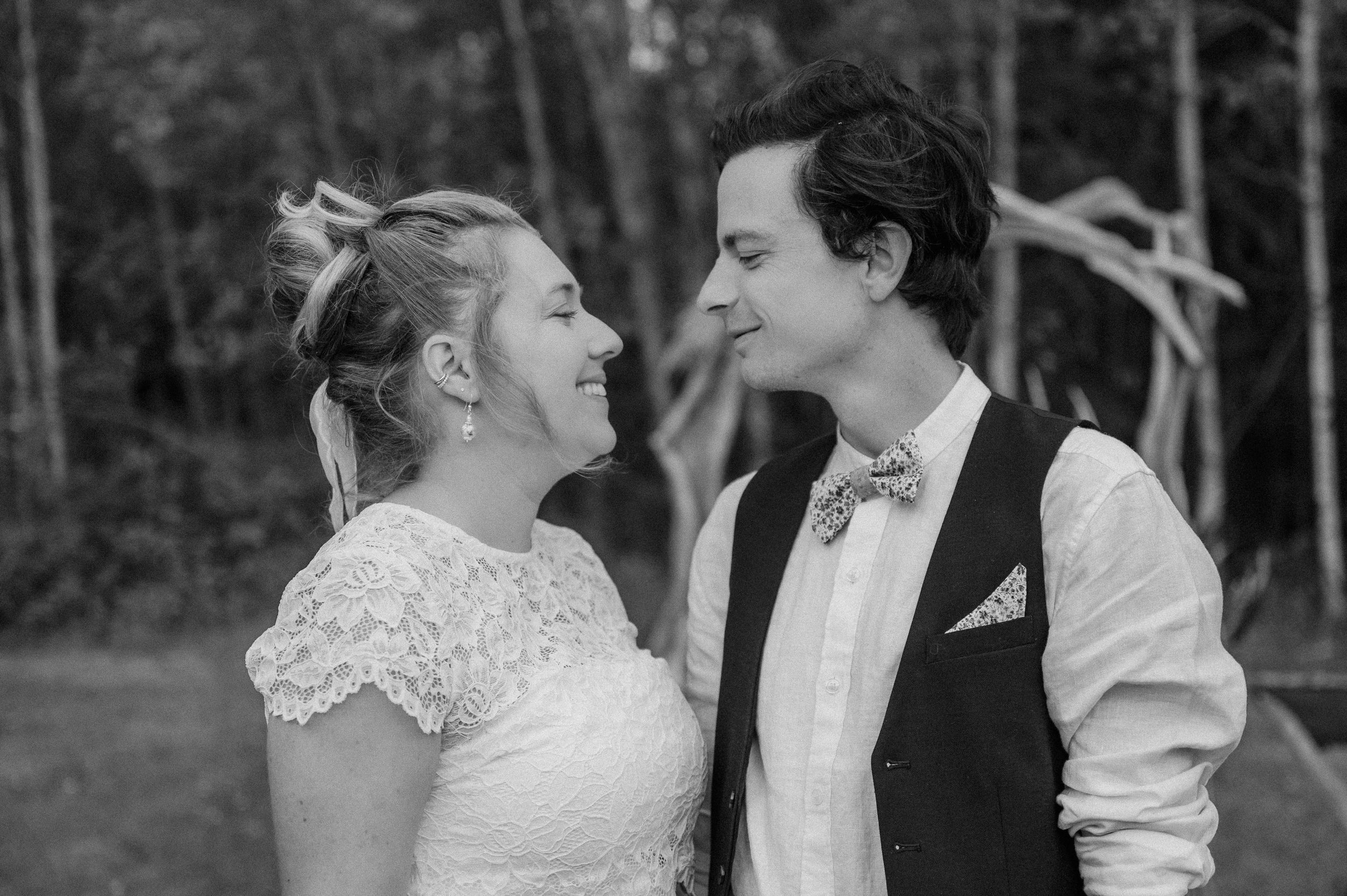 A joyful black and white wedding photo shows a happy couple in wedding attire sharing an intimate moment outdoors.