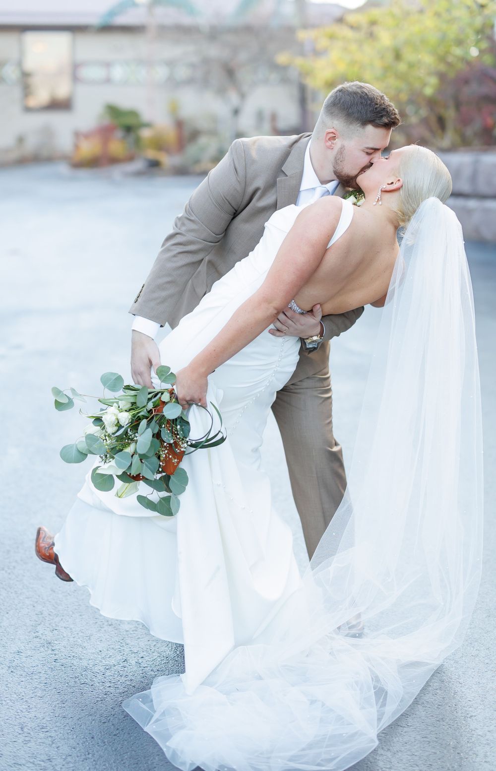 A romantic wedding dip pose featuring white eucalyptus bouquet and flowing veil.