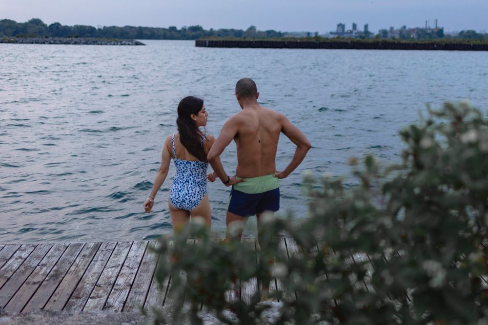 A couple considers jumping into Lake ontario as they stand on a dock in their swimsuits at Lake Ontario, Kingston, Ontario, Canada.