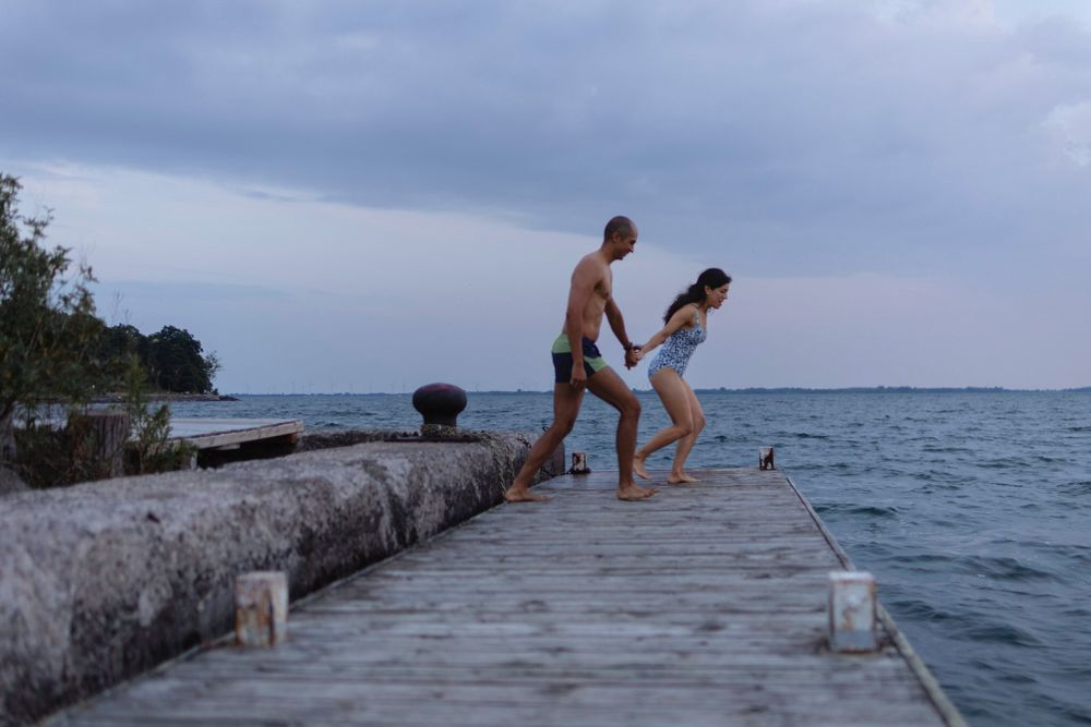 A couple holds hands as they run to jump off a dock into Lake Ontario, in Kingston, Ontario, Canada.