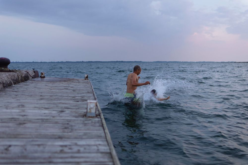 A couple lands in the water after jumping off a dock alongside Lake Ontario in Kingston, Ontario, Canada. There's a large splash.