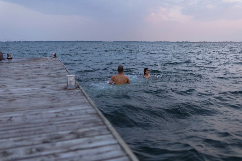 A couple lands in the water after jumping off a dock alongside Lake Ontario in Kingston, Ontario, Canada.