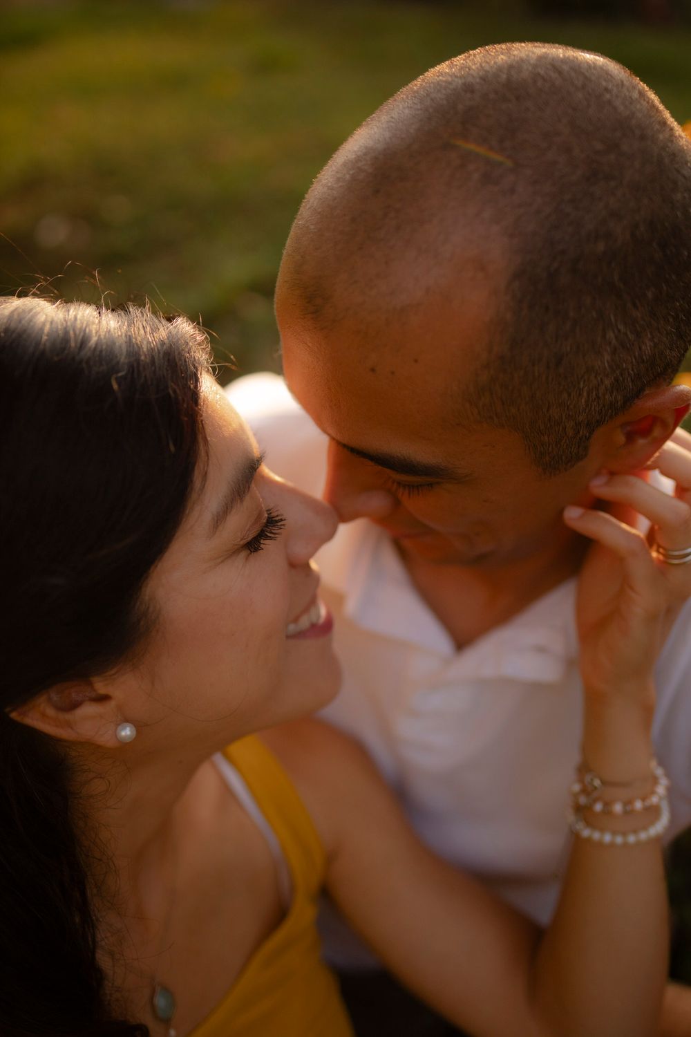 Couple sits among yellow flowers at sunset/golden hour. Tight shot of them sitting nose to nose at Lake Ontario, Kingston, ON, CA.