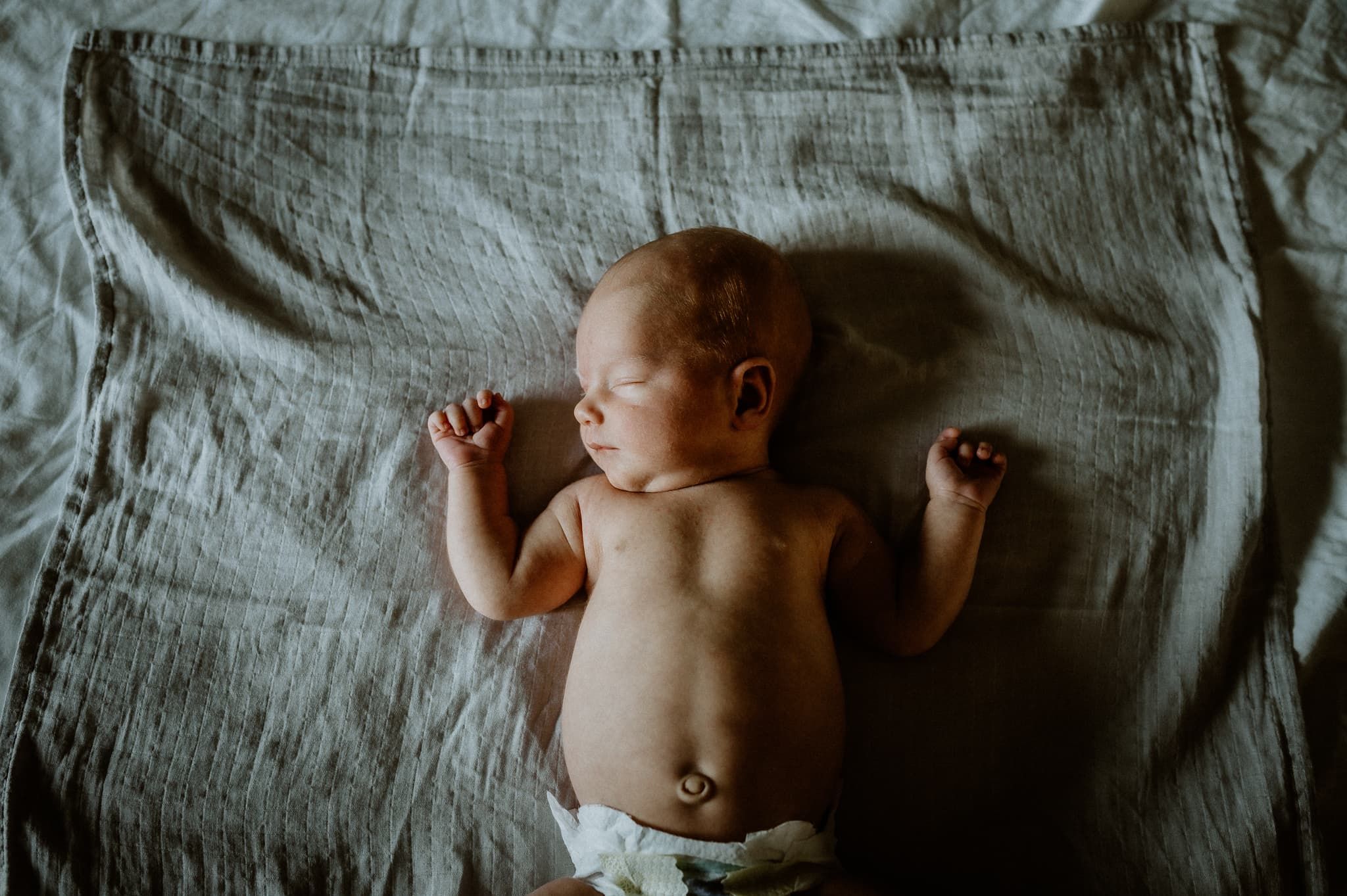 Nyfödd bebis ligger på en säng i fönsterljus, under en nyföddfotografering med Fotograf Veronica Eng, Mullsjö, Jönköping.