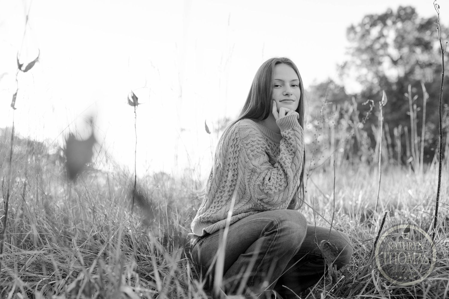 Black and white candid photo of someone laughing while sitting in a grassy field.