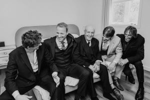 A group sits together on a couch sharing laughter during wedding festivities.