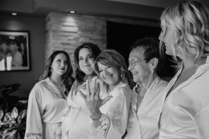 Wedding party members in white robes share a candid moment together.