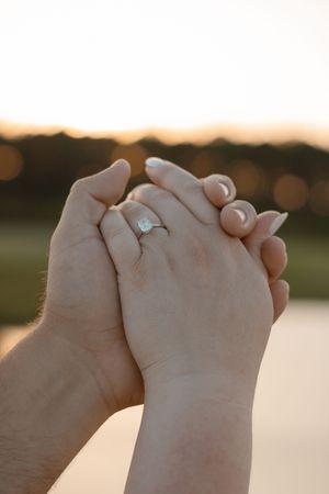 Close-up sequence of hands holding together with engagement ring visible at sunset.