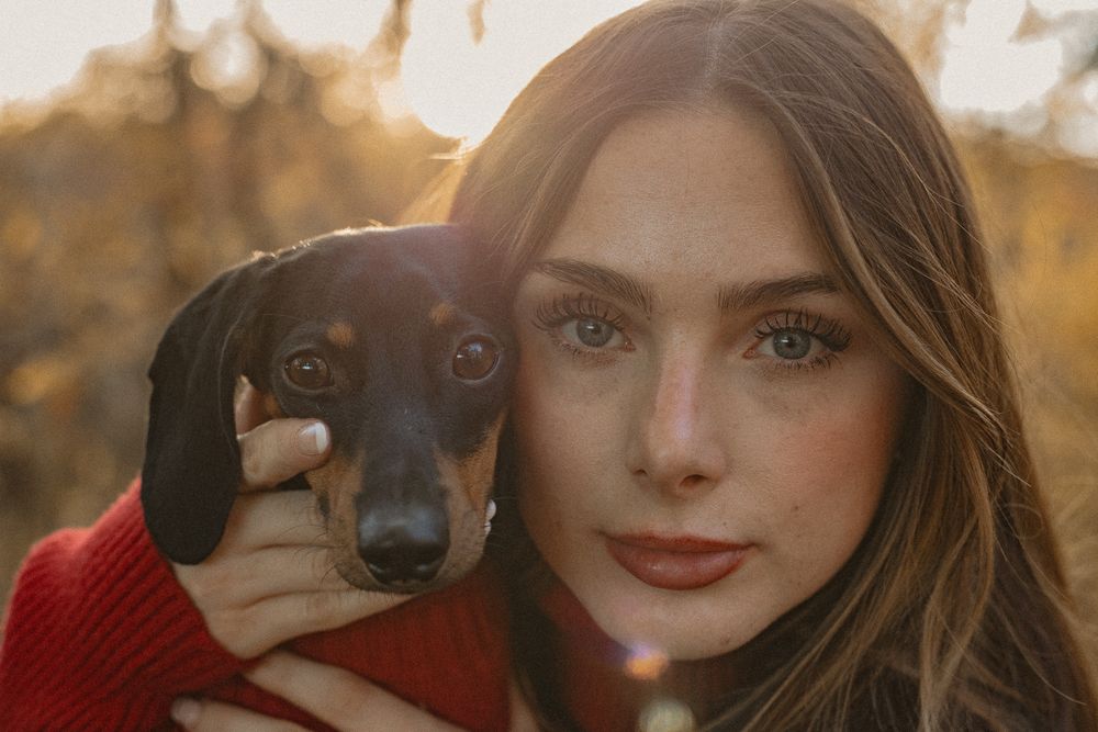 Dachshund in red sweater with person in autumn outdoor portrait.