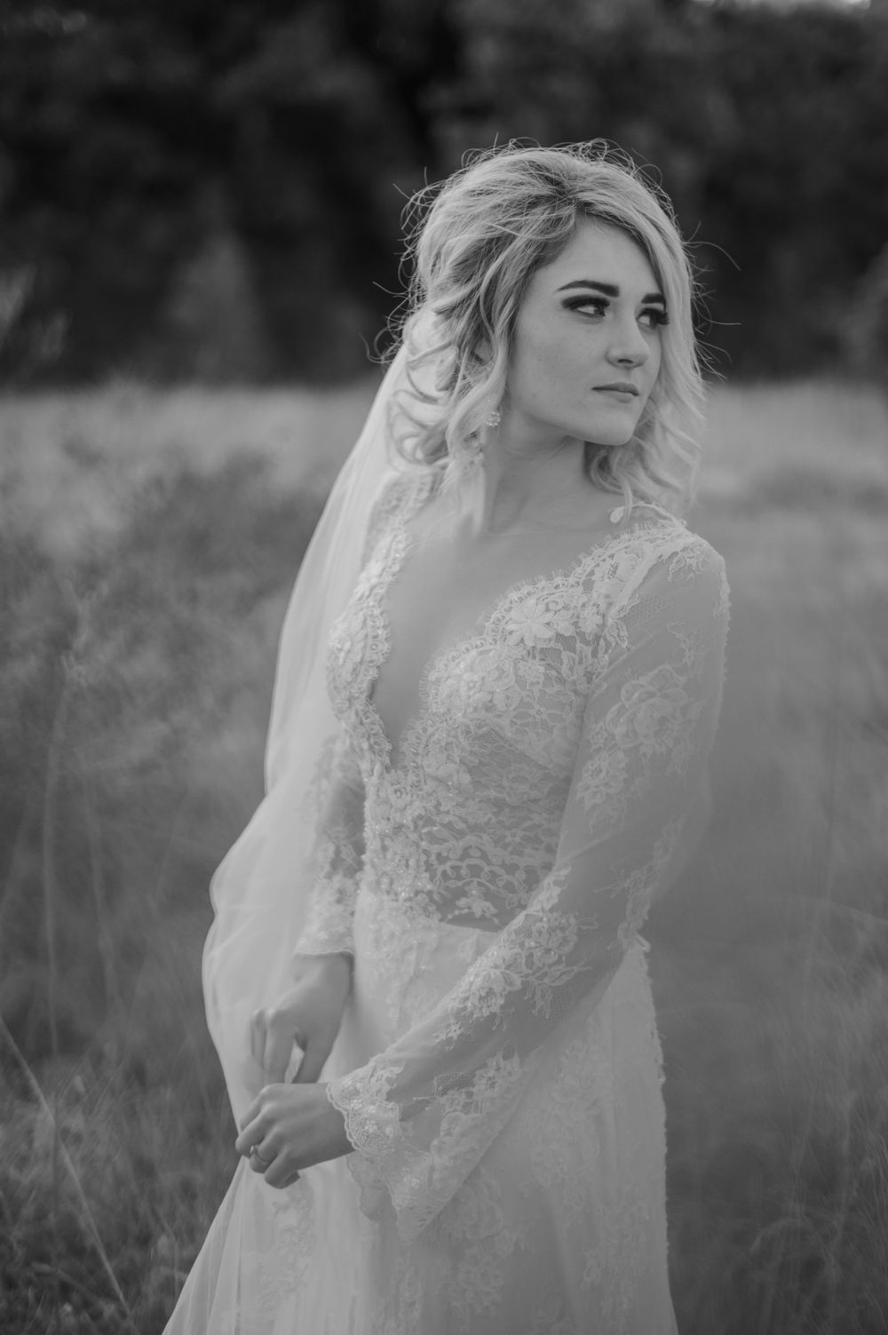 Black and white portrait of bride wearing lace long sleeve wedding dress and veil.