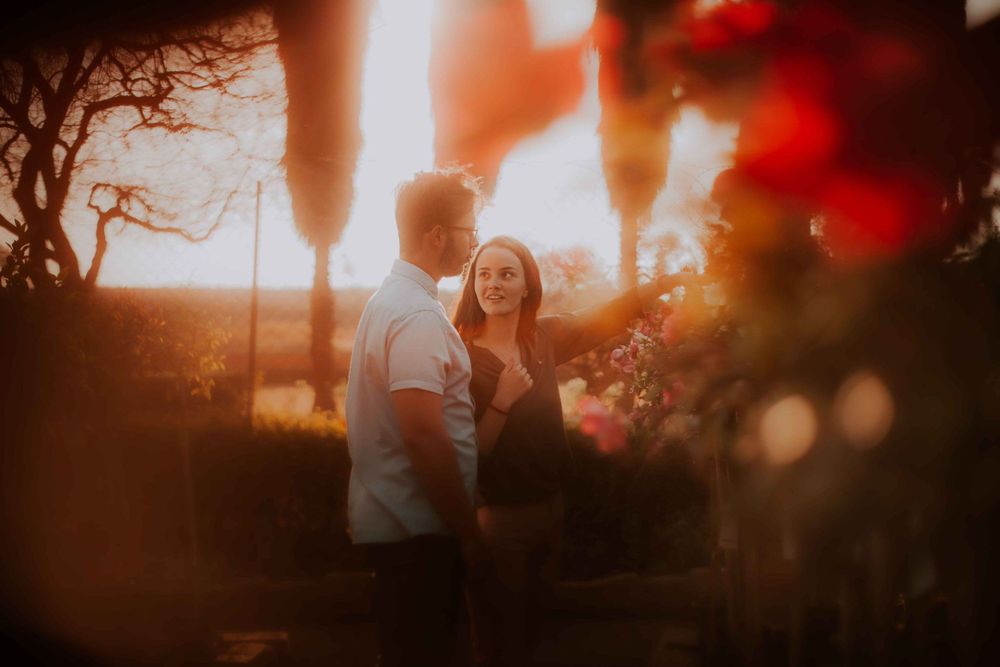 A warm sunset engagement photo with bokeh lights creating a dreamy romantic atmosphere.