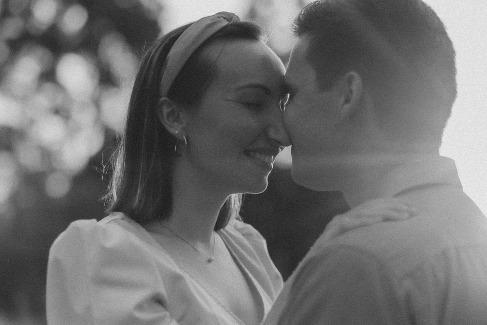 Intimate black and white portrait of a couple sharing a tender moment in natural lighting.