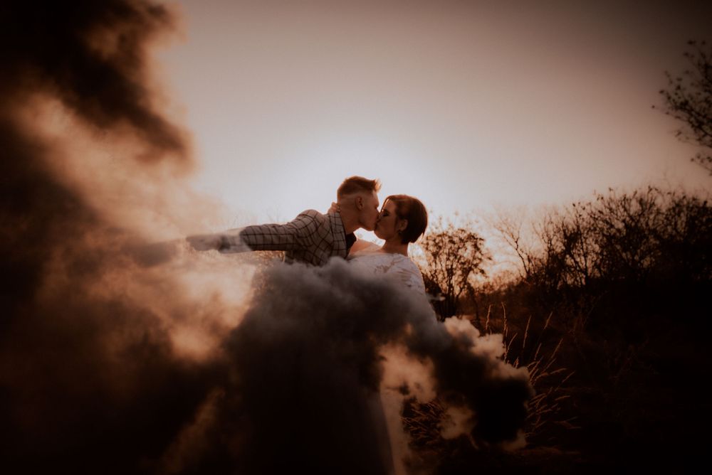 Romantic silhouette of a couple embracing against a moody sunset sky with dramatic clouds.