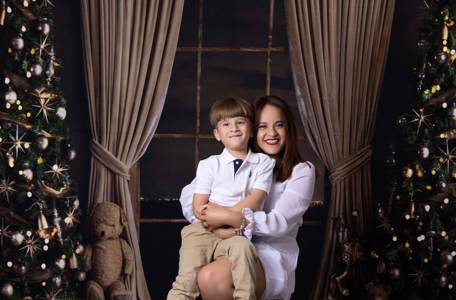 Christmas themed family portrait session with decorated tree and white curtains.