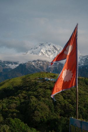 Nepali flags wave against a backdrop of snow-covered Himalayan peaks.