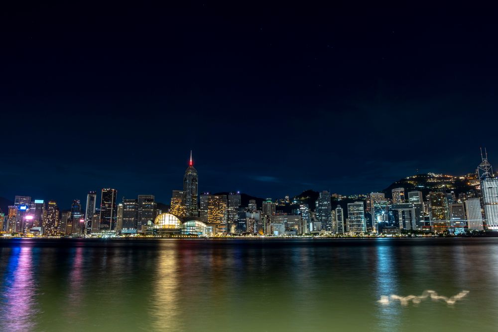 Nočný pohľad na osvetlený Hongkong s odrazmi svetiel na hladine vody – mesto žiari ako moderná perla južnej Číny.