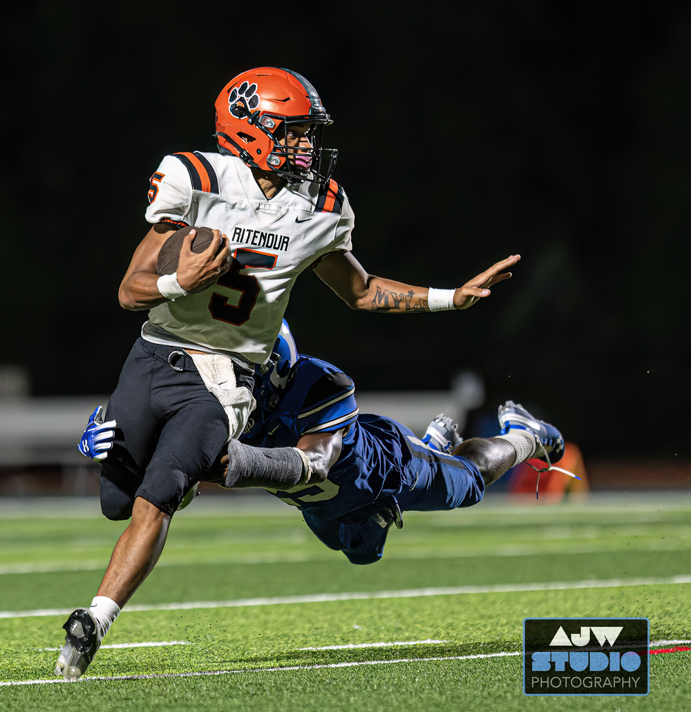 Player in orange and white uniform breaks tackle attempt during football game.
