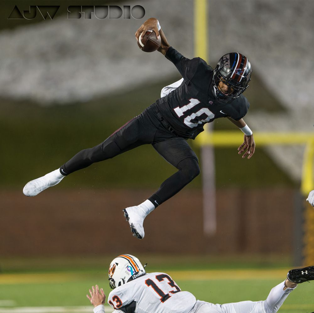 Football player leaps horizontally over defender while throwing the ball during game action.