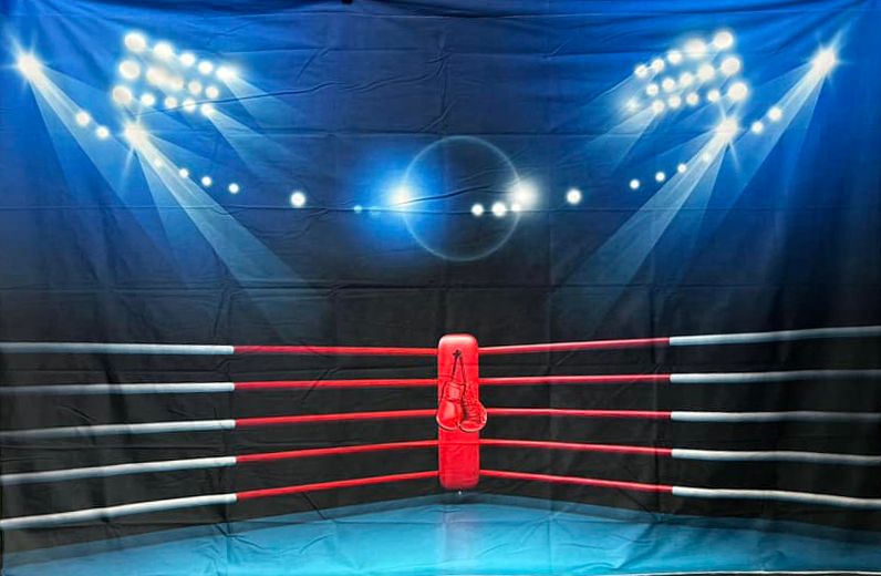 Empty boxing ring with dramatic blue lighting and ropes illuminated by stadium lights.