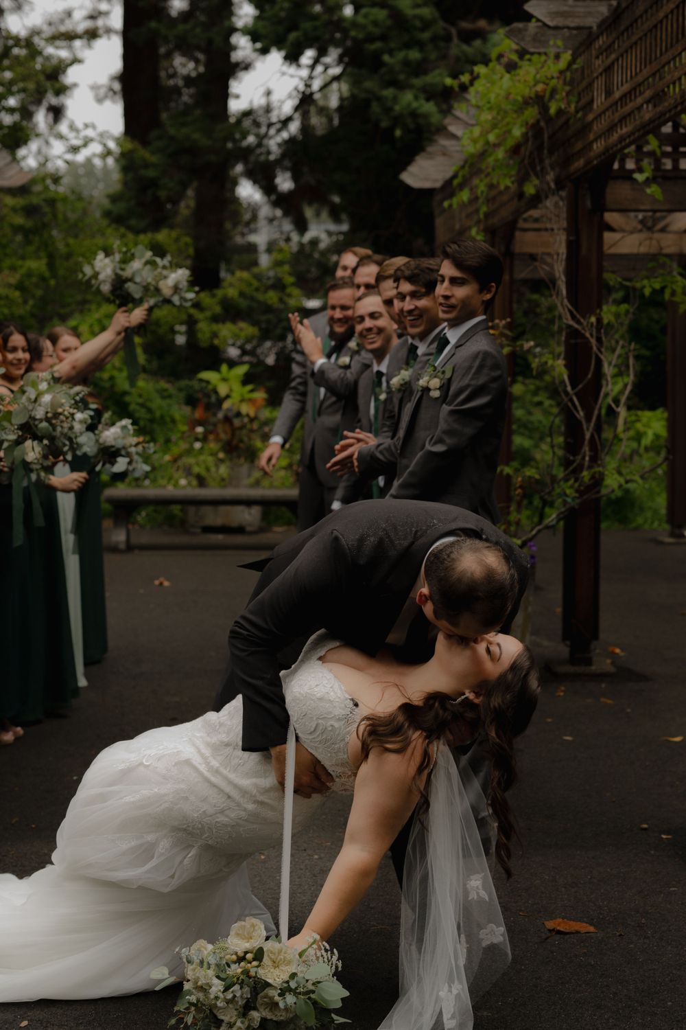A dramatic dip dance move performed during a wedding celebration under a rustic wooden pergola.