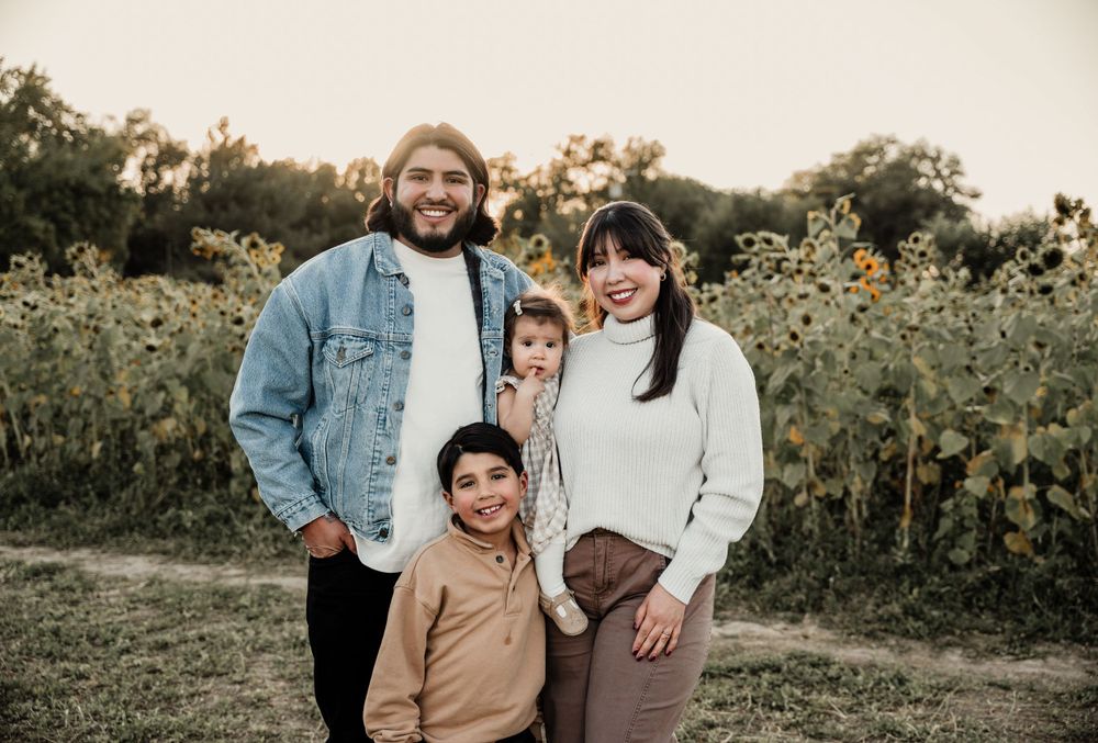 Family portrait session captured in a field of sunflowers at sunset.