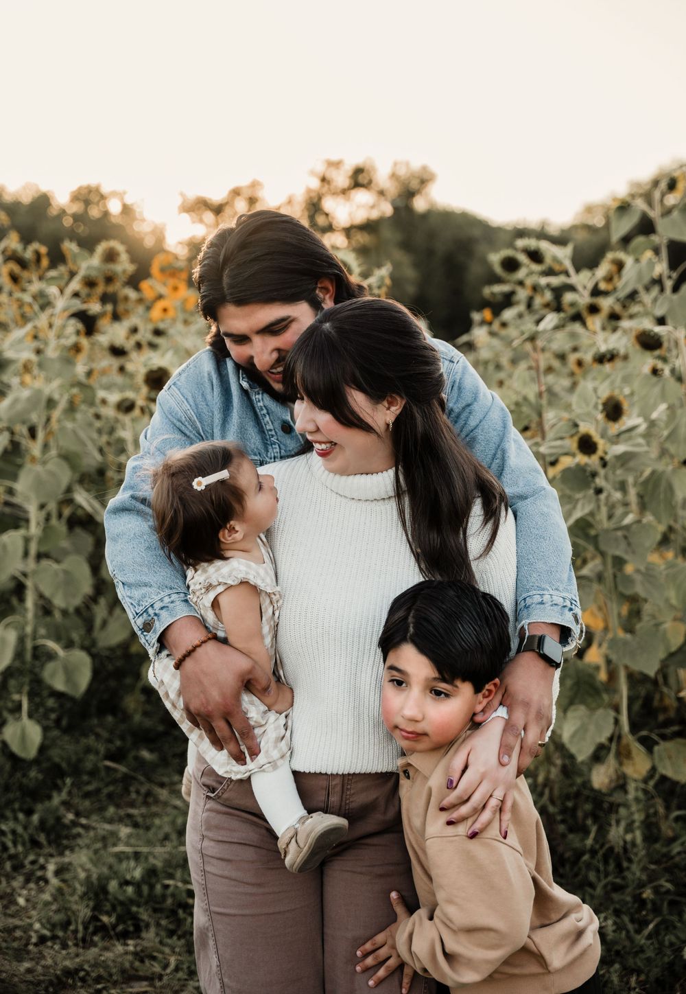 Sweet family embraces during an outdoor photo session among sunflowers.