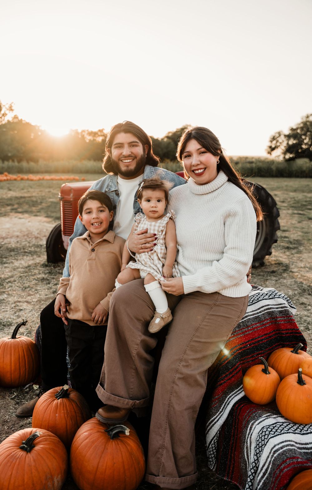 Autumn family photo session with pumpkins and sunflowers at sunset.