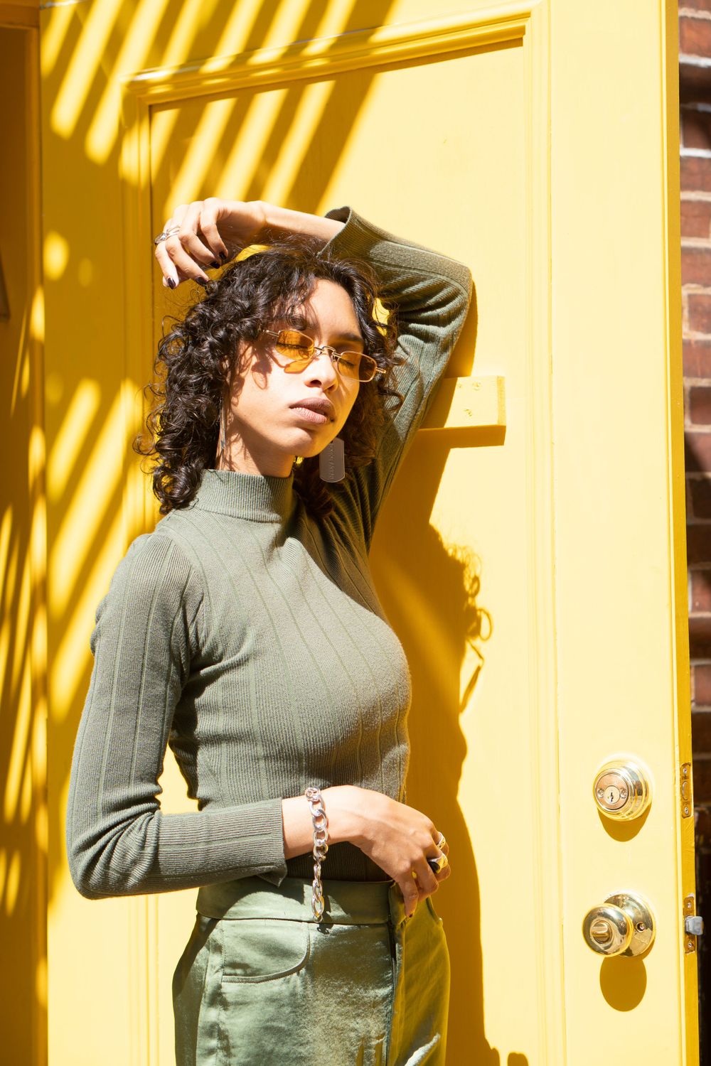 Stylish portrait against yellow door with dramatic shadow patterns.