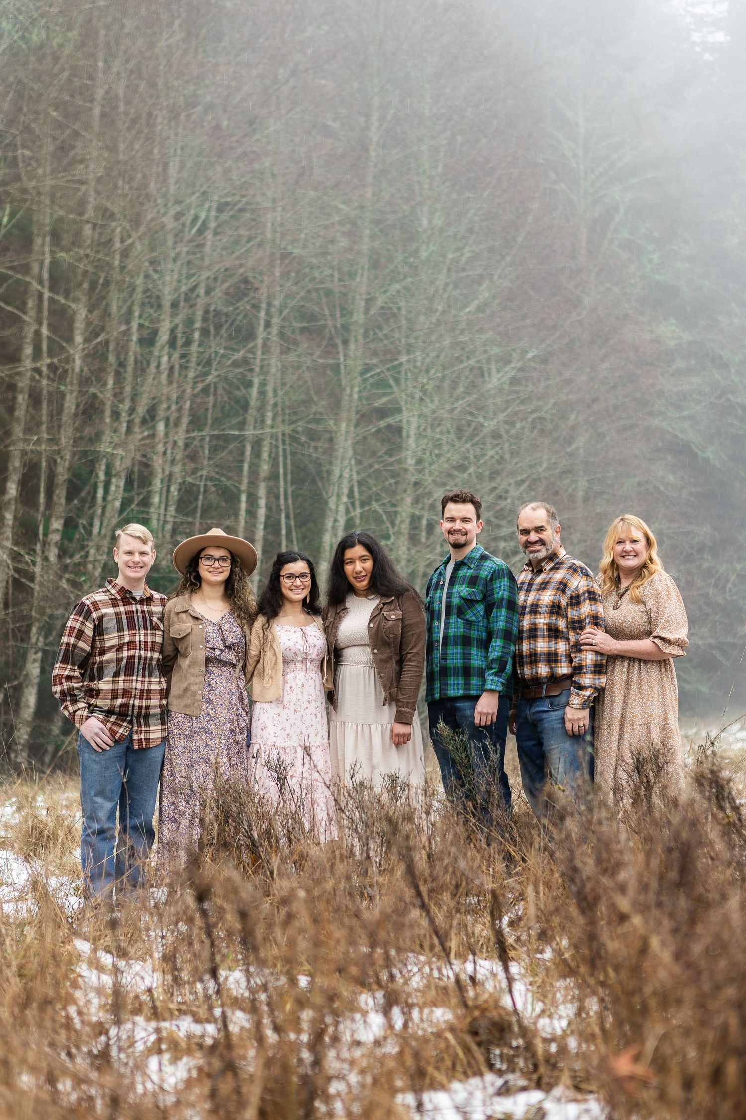 Group of people in coordinated outfits standing together in a winter field with bare trees in background.