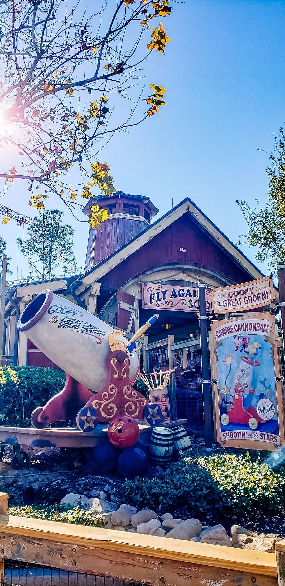 Whimsical wooden signs with circus-themed decorations and designs line a rustic fence at an outdoor attraction.