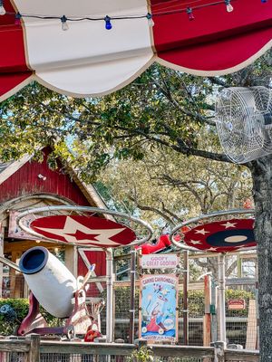 Carnival ride canopy with red and white stripes featured alongside spinning seats at an amusement park attraction.
