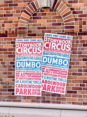 Two vintage red and blue Storybook Circus Dumbo posters displayed against a brick wall beneath an arched architectural detail.