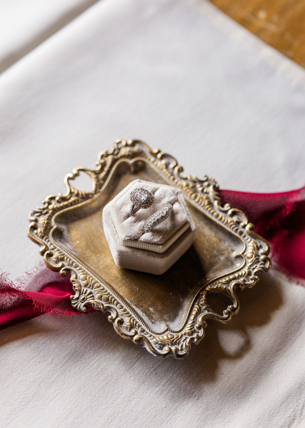 Ornate vintage silver tray holding a small decorative ring box with floral details.
