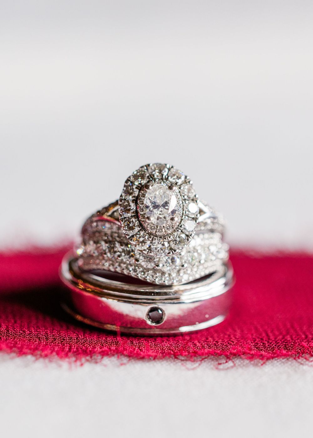 Diamond wedding ring set with intricate halo design displayed on red fabric.