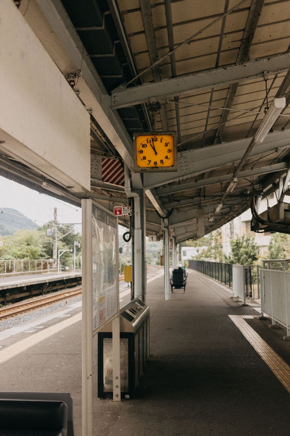 Empty train platform with yellow clock and mountains visible in the background.