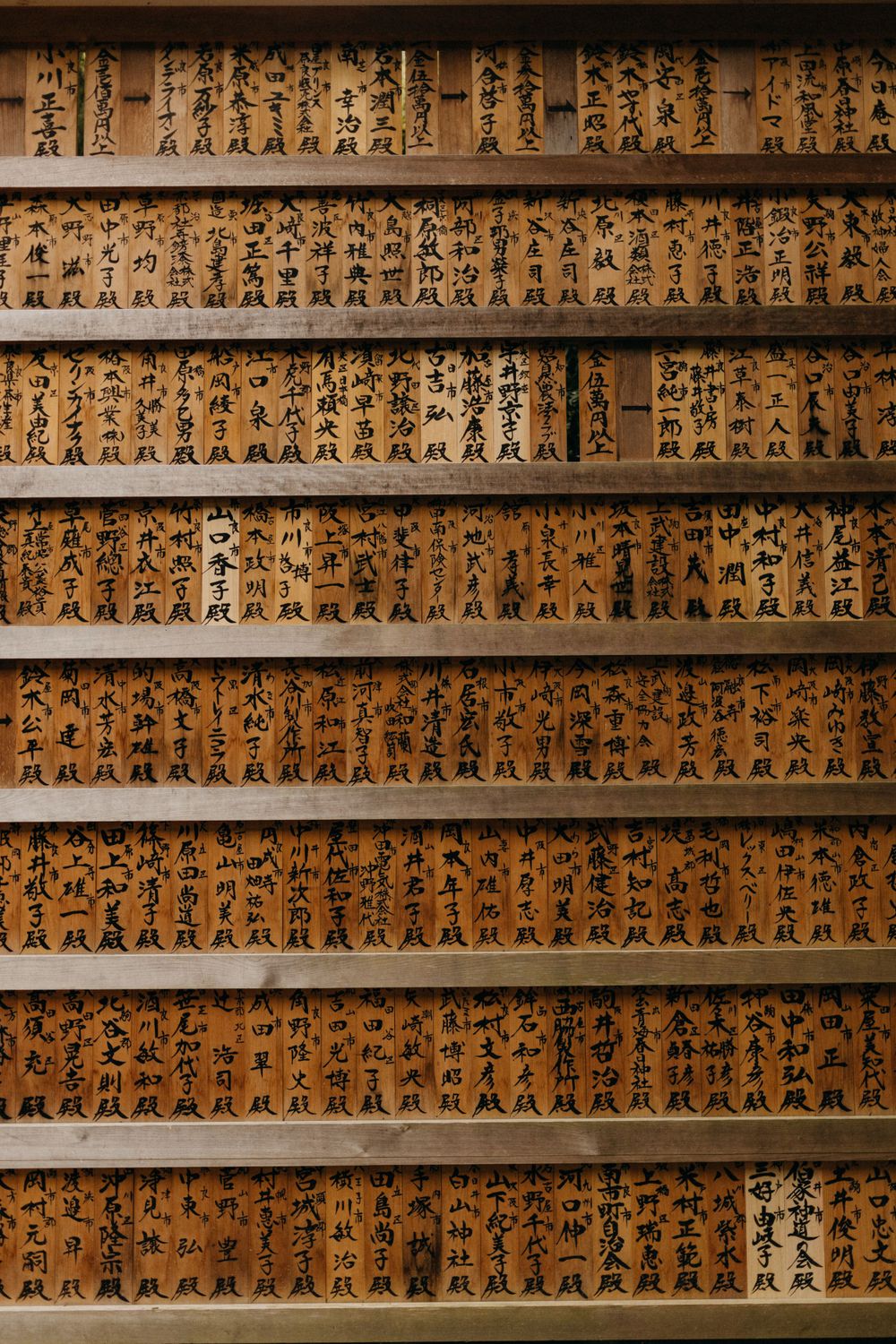 Wooden panels display rows of traditional Japanese calligraphy characters in warm brown tones.