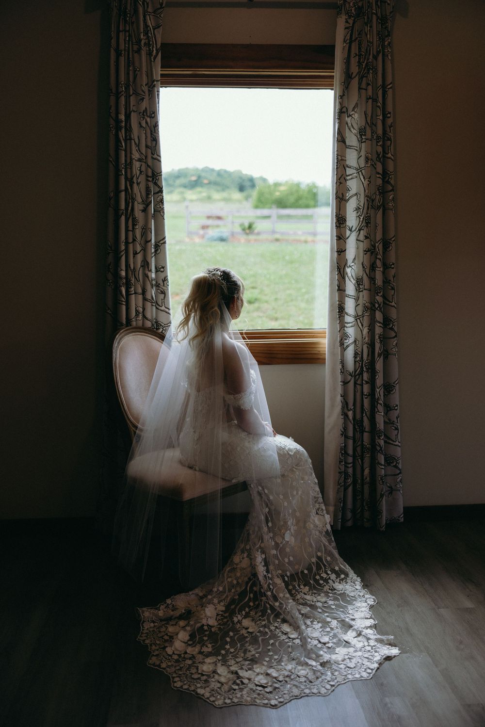 A flowing lace wedding dress with veil silhouetted against a window in a dark room. Estate and historic venue wedding photographer