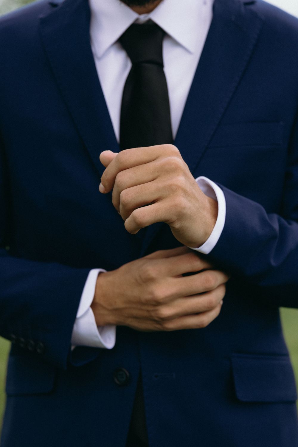 Close-up of hands adjusting sleeve cuff on navy suit. Estate and historic venue wedding photographer for NC and across the East Coast