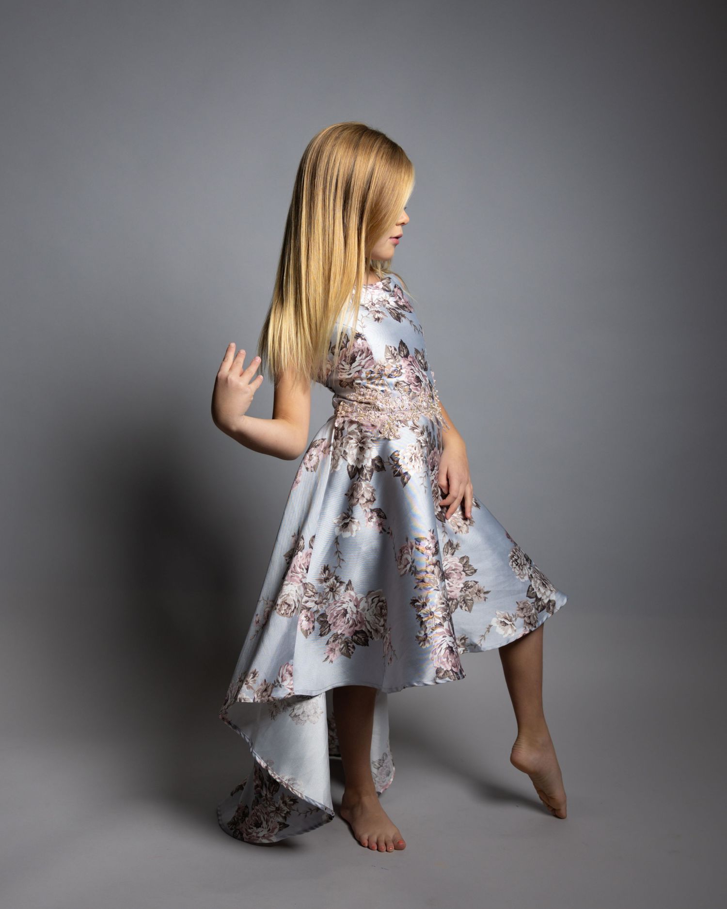 Girl in floral dress poses elegantly during studio portrait session.