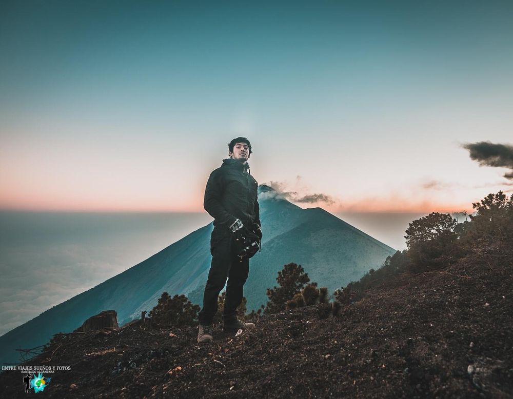 Silhouette against sunset sky with mountain peak in background.