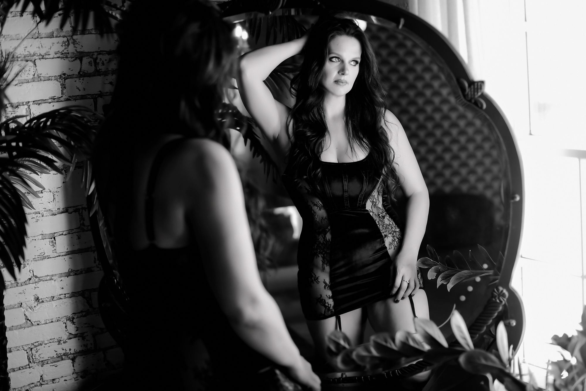 Black and white boudoir photo with ornate mirror.