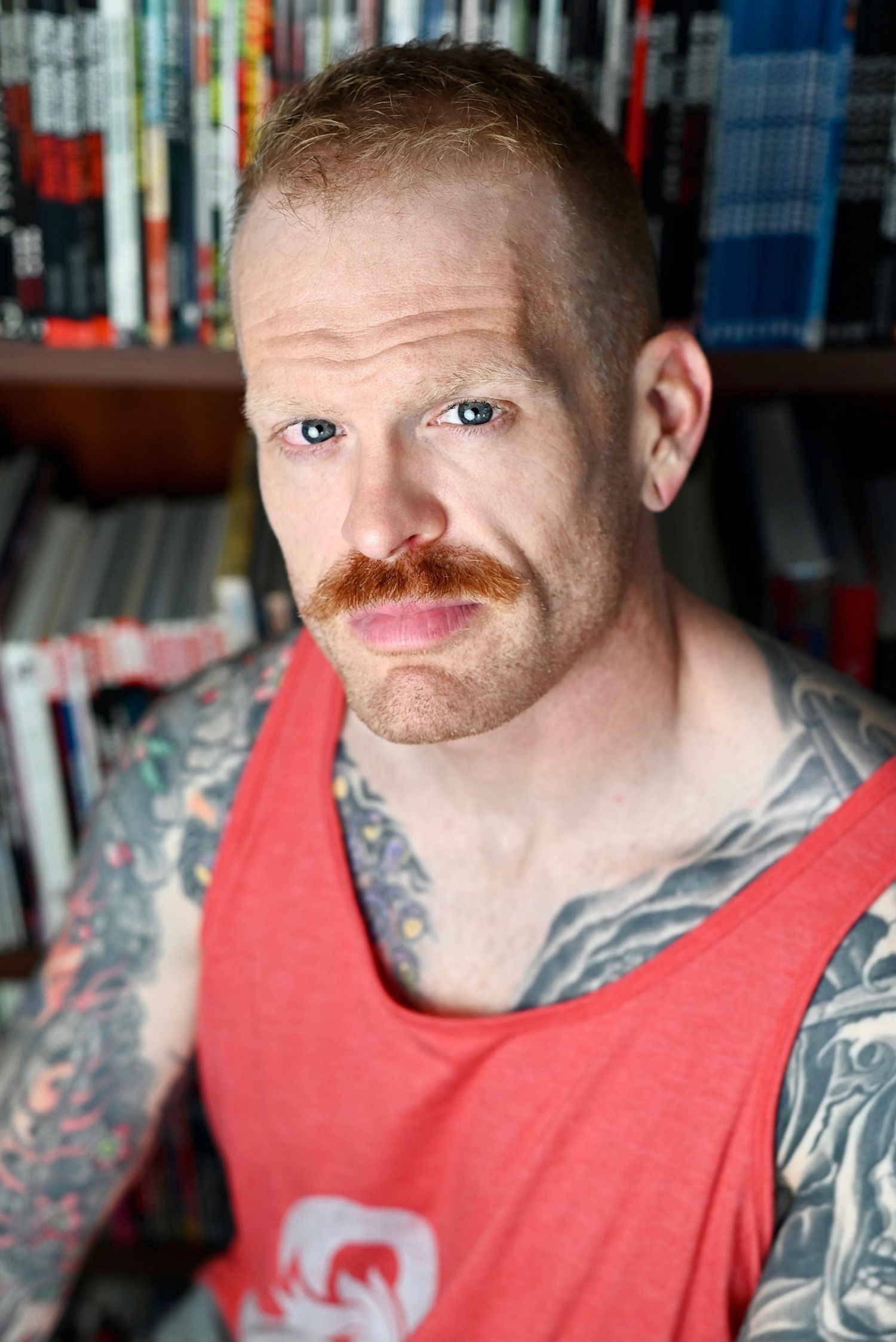 Person in a red tank top with neck tattoos looking at camera in a series of closeup shots.