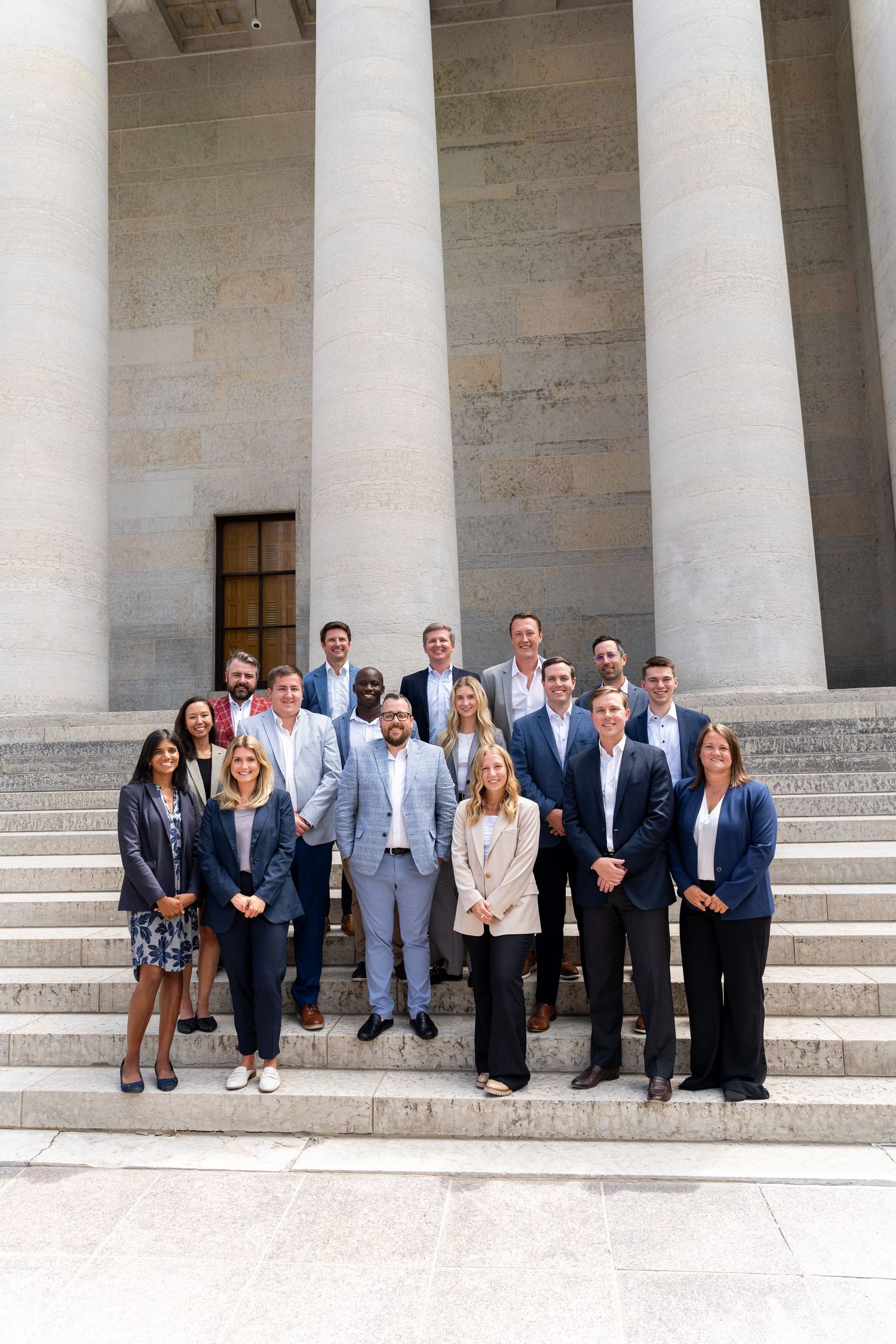 A professional group photo of business people standing on stone steps of a government building.