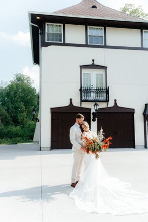An elegant wedding portrait against a white and brown architectural backdrop with a flowing dress.