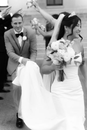 A joyful wedding moment captured in black and white showing celebration with a bouquet and formal attire.