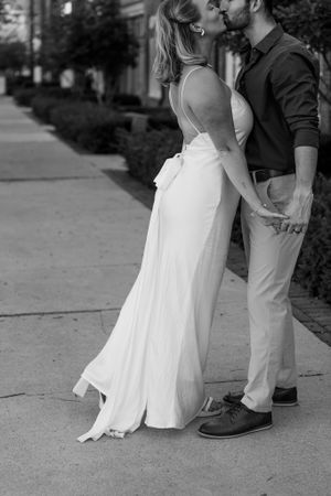 Black and white photo of a romantic dance pose highlighting an elegant wedding dress and formal attire.