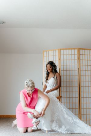 A tender moment of wedding preparation as final touches are made to the bridal gown.