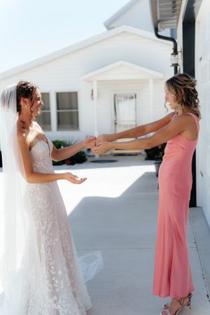 Two people in formal attire sharing a joyful moment on a white porch during a wedding celebration.