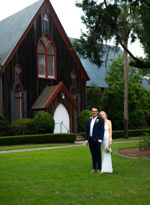 A romantic wedding couple shares intimate moments in front of a rustic red church with Gothic architecture.
